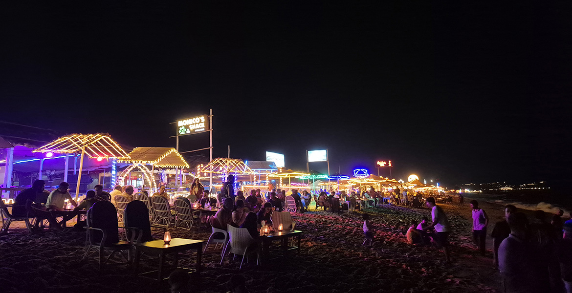 Colorful beach shacks, restaurants and nightlife crowd along the beach in Goa at night