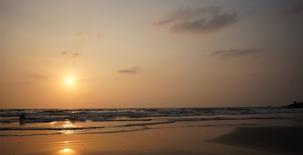 Sunset over the sea at a Goa beach with golden reflections on the waves and wet sand