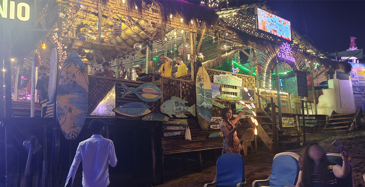 Beachfront bar in Goa with vibrant nightlife, live entertainment, colorful lights, and outdoor seating