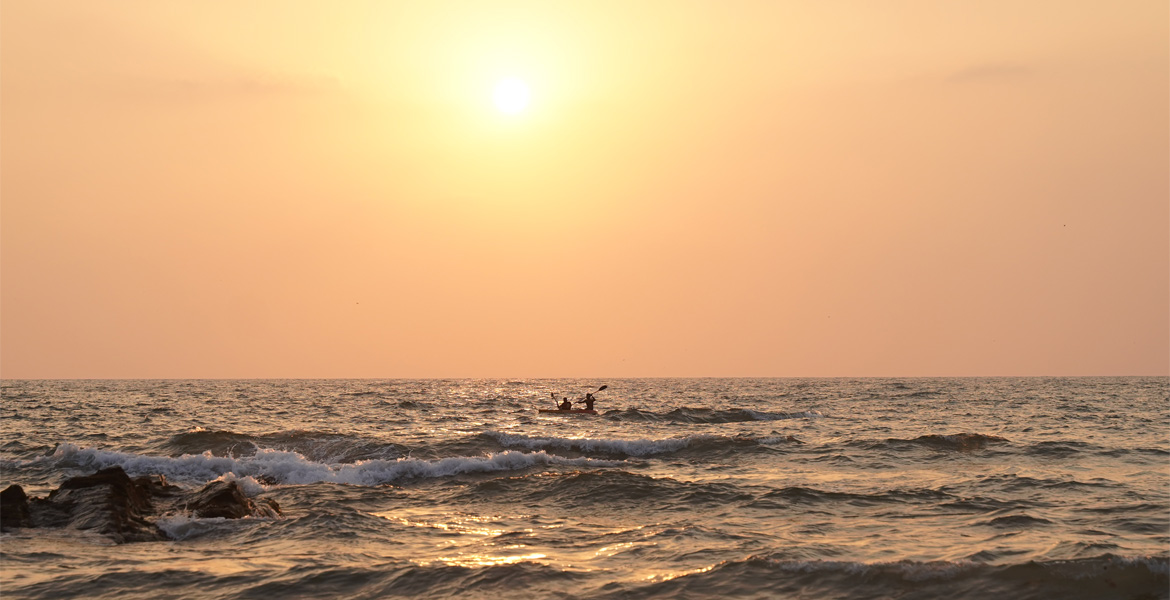 Sunset over the sea with waves and a kayak in Goa