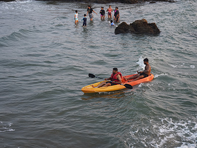 People kayaking near the rocky shoreline at Ozran Beach in Goa