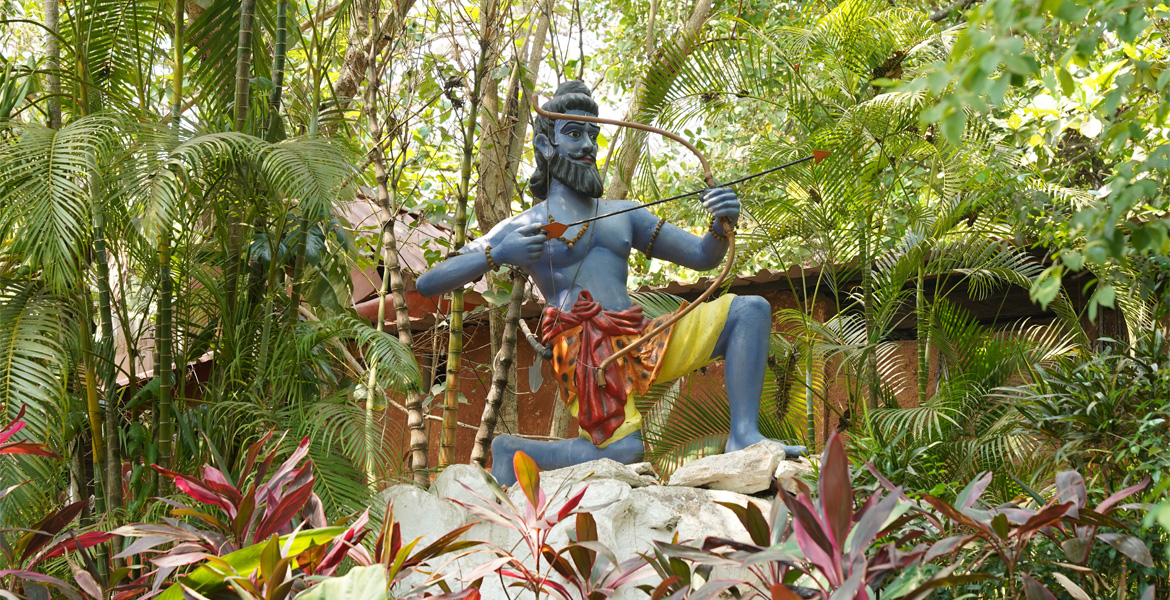 Lord Rama statue with bow and arrow surrounded by lush greenery at Ancestral Goa (Big Foot Goa) in Loutolim
