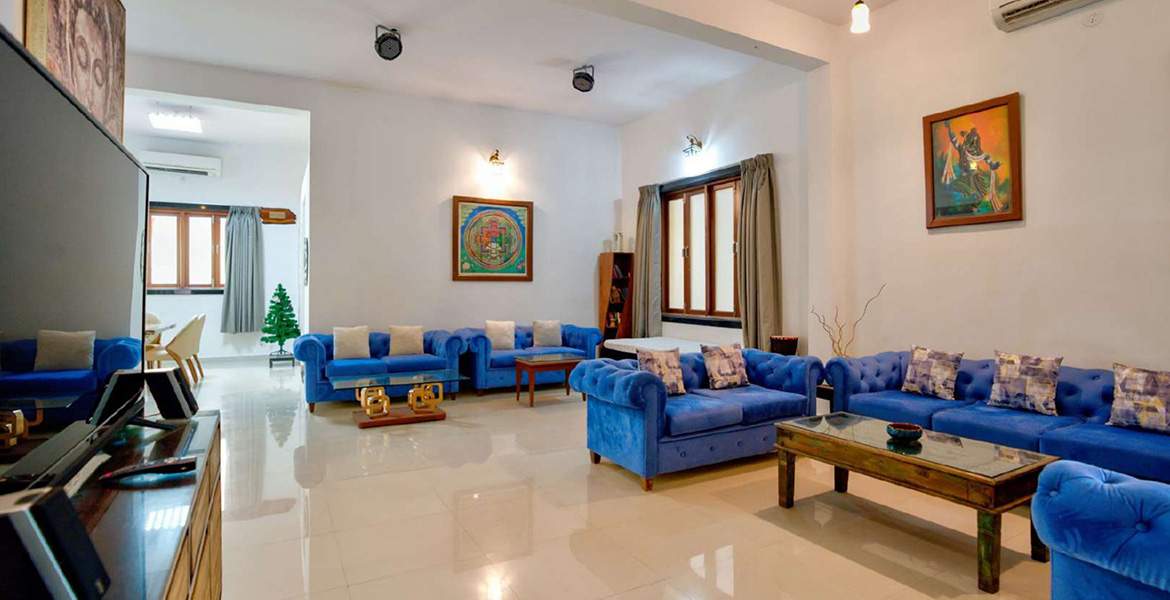 Spacious luxury villa living room in Morjim, Goa with blue sofas, modern interiors, and large seating area