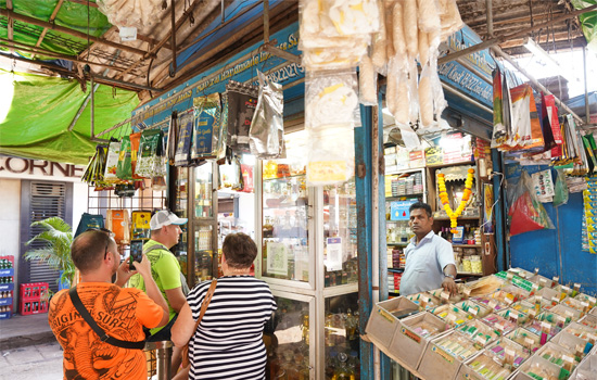 Visitors shopping at Mapusa Market in Goa with stalls selling spices, souvenirs, handicrafts, clothing, and local products