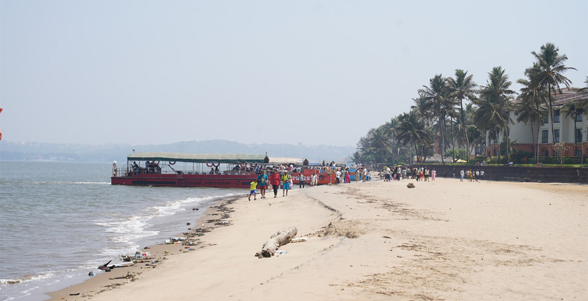 A large tourist boat docked along the shoreline of Miramar Beach in Panaji, Goa