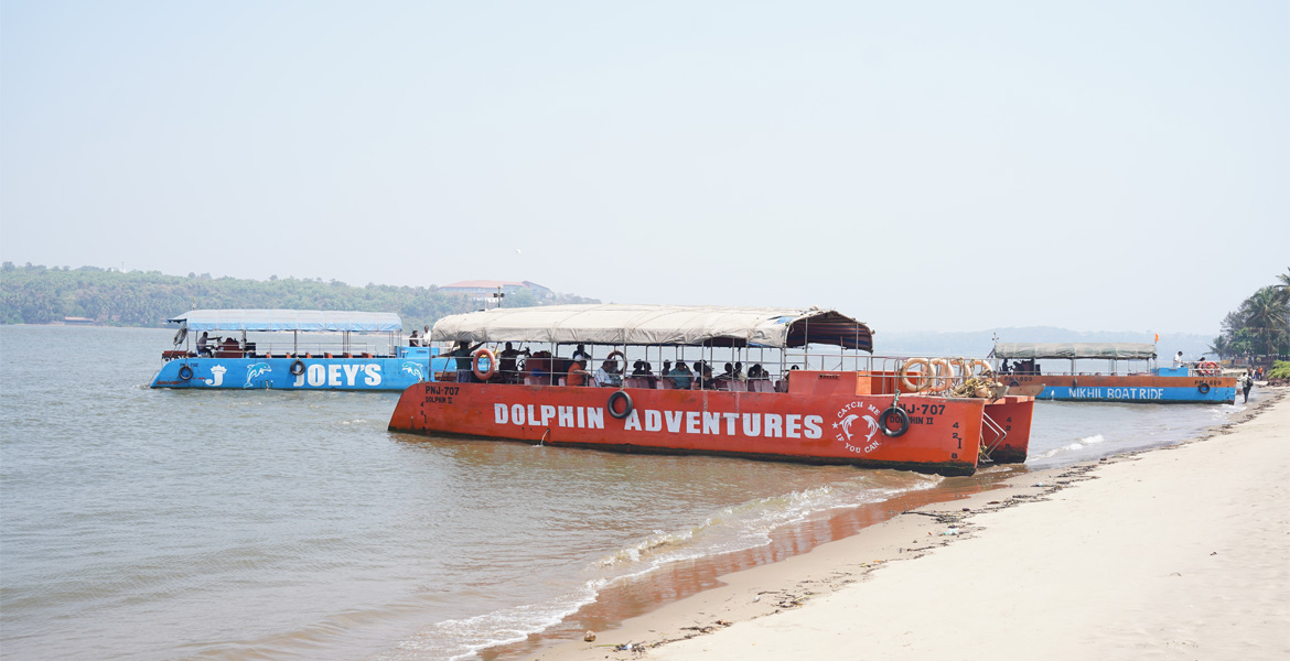 Tour boats anchored along the shoreline at Miramar Beach Goa with calm coastal and river views