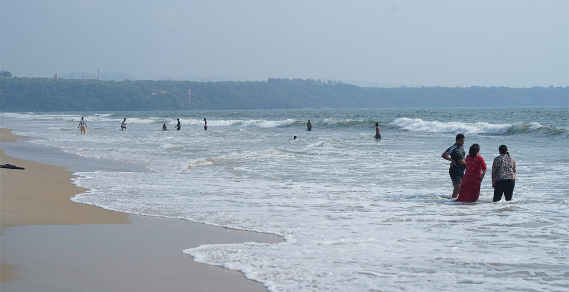 Visitors enjoying waves at Mobor Beach, Goa