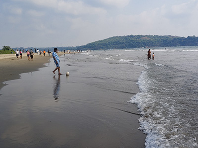 Man playing football along the shoreline at Morjim Beach in Goa