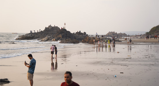 Visitors exploring the rocky shoreline and enjoying the sunset views at Ozran Beach Goa