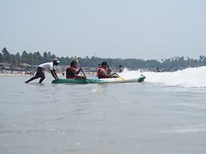 People kayaking through waves at Palolem Beach, Goa