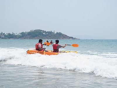 People kayaking through waves at Palolem Beach, Goa