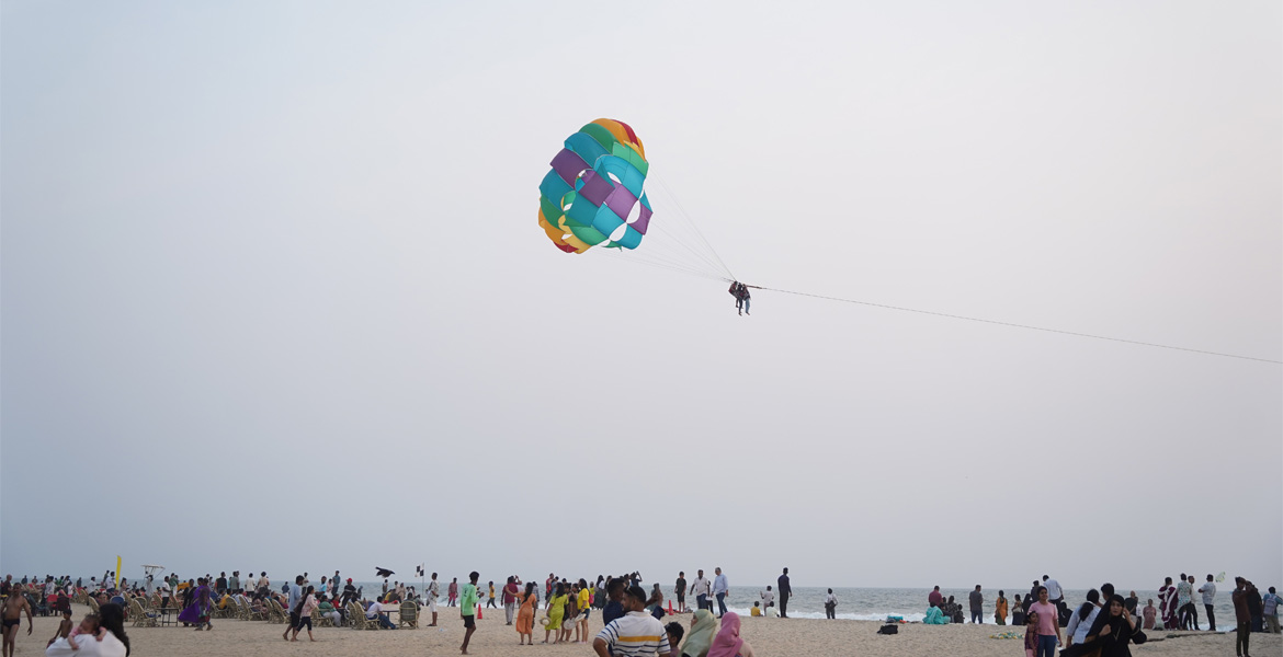 Tourist parasailing above crowded beach