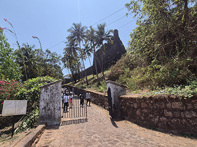 Entrance pathway leading to the historic Reis Magos Fort in Goa surrounded by palm trees