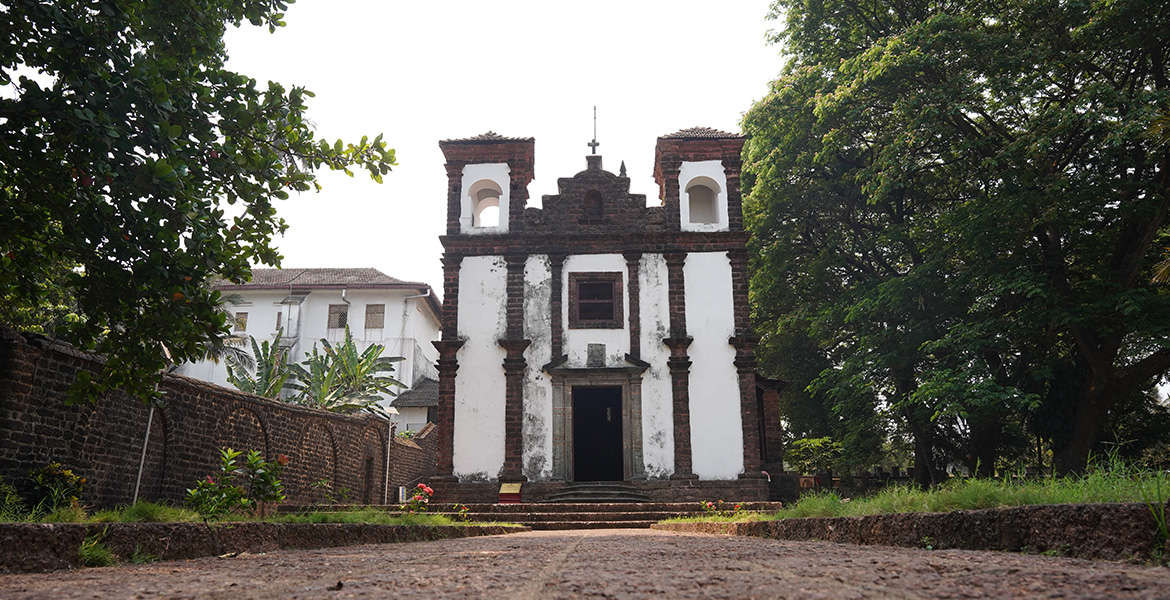 Front view of the historic Se Cathedral church in Old Goa surrounded by trees