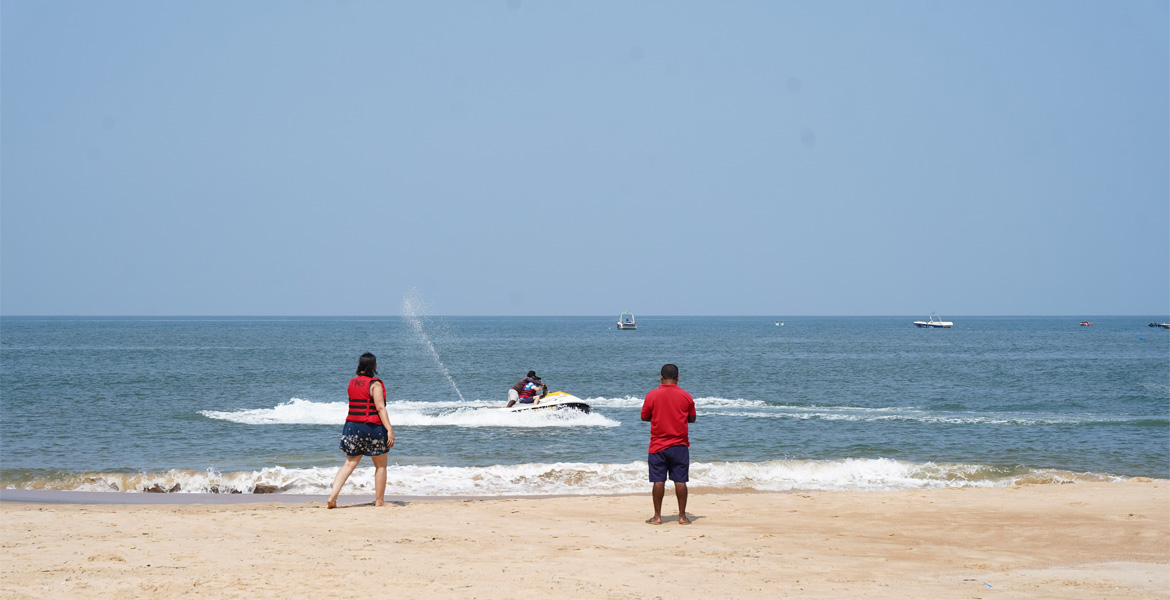 Visitors watching a jet ski ride on the Arabian Sea at Sinquerim Beach Goa, a popular water sports destination