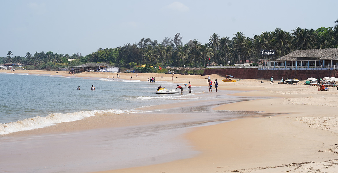 Visitors enjoying the sandy shoreline, gentle waves, and coastal scenery at Sinquerim Beach Goa