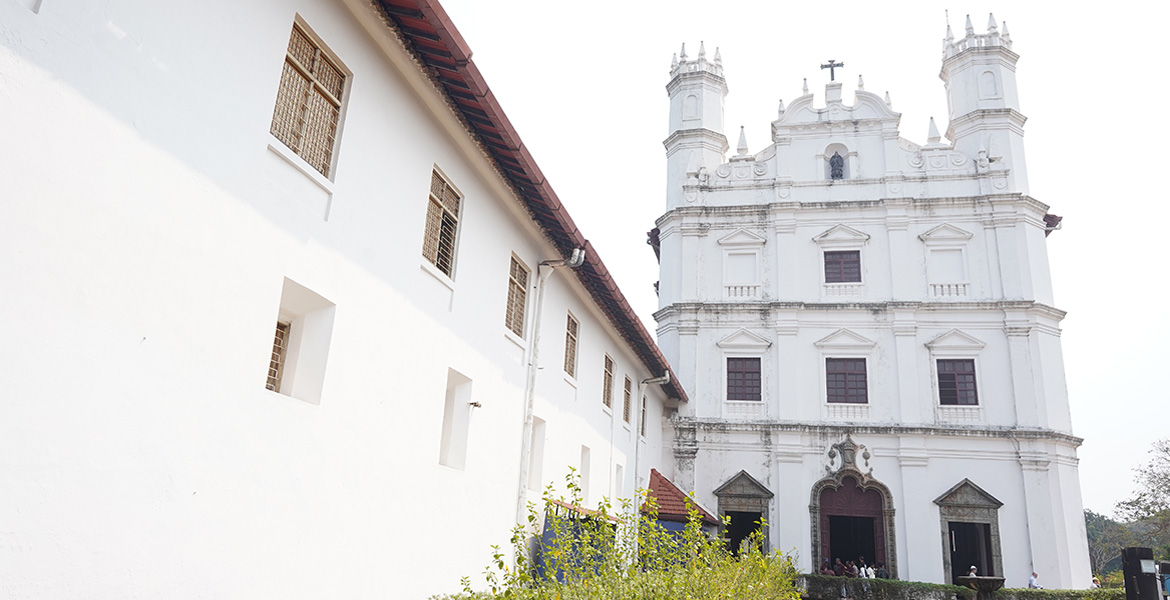 Side view of St. Francis of Assisi Church in Old Goa showcasing its white Portuguese-style facade and bell towers