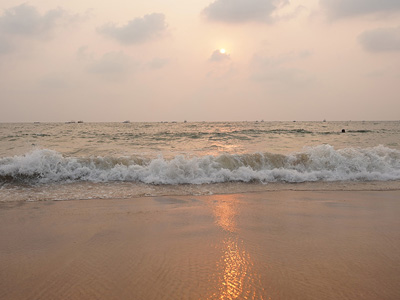 Golden sunset reflection on the wet sand shoreline of Candolim Beach in Goa.