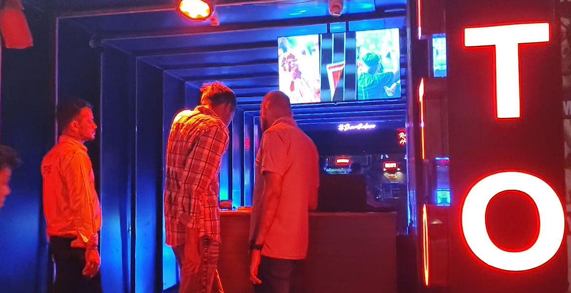 People entering a neon-lit nightclub entrance at Tito’s Lane in Goa during night