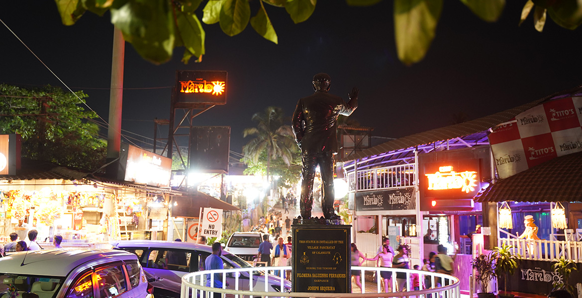 Nightlife street with Tito’s Lane, clubs, restaurants and illuminated statue area in Goa at night