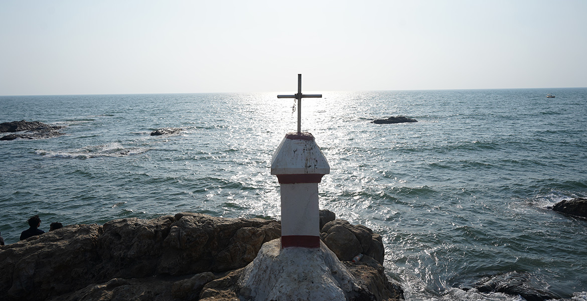 Cross monument on the rocky shoreline overlooking the Arabian Sea at Vagator Beach, Goa.