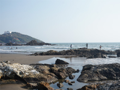 Rocky shoreline, tide pools, and Arabian Sea views at Vagator Beach Goa with visitors exploring the coast