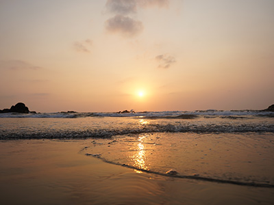 Golden sunset over the Arabian Sea at Vagator Beach with gentle waves and reflections on the sandy shore in North Goa