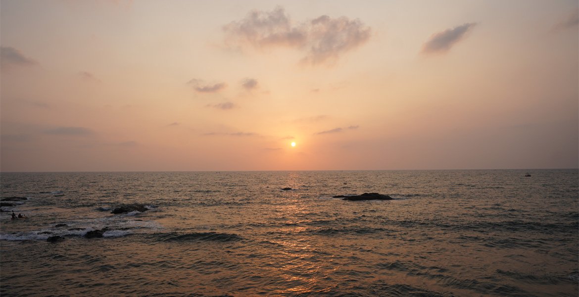 Sunset over the Arabian Sea at Vagator Beach in Goa with rocky shoreline and golden reflections on the water