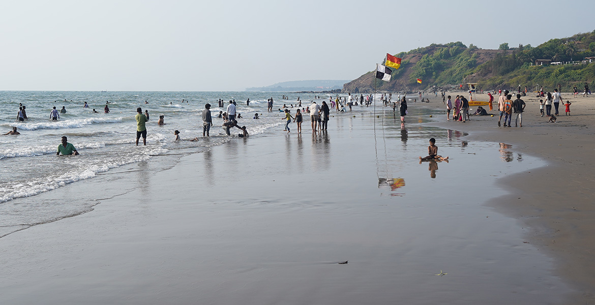 Tourists enjoying the shoreline and sea waves at Vagator Beach in Goa