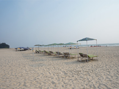 Beach sunbeds with shaded canopies on the sandy shoreline of Varca Beach Goa