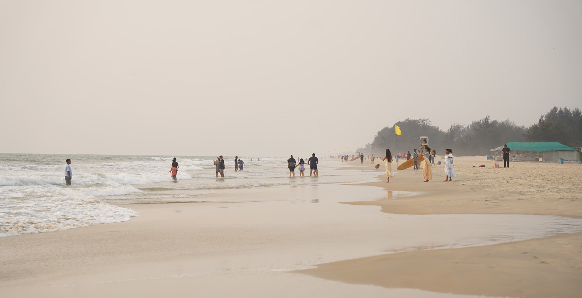 Visitors enjoying the shoreline at Varca Beach, Goa