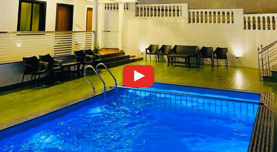 Modern villa at night with a lit swimming pool and outdoor seating area