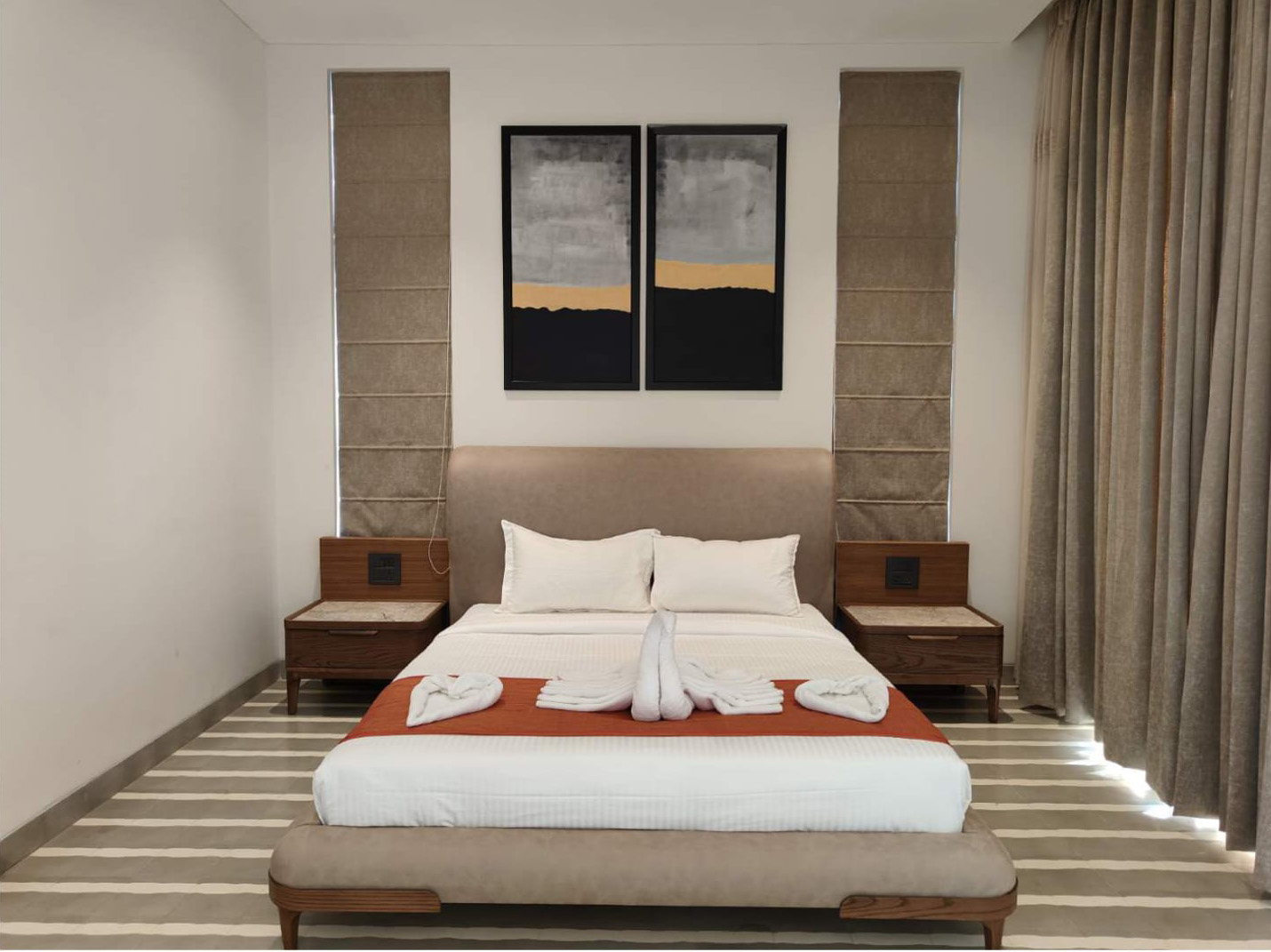 Symmetrical bedroom view with a bed, nightstands, and twin abstract art pieces.