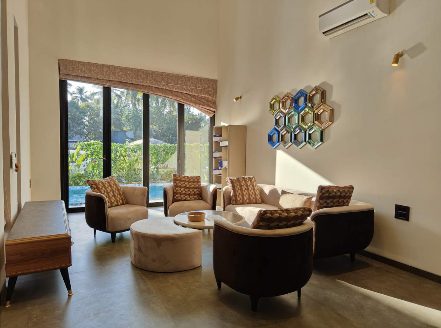 Living room with modern seating and a large window view of a pool.