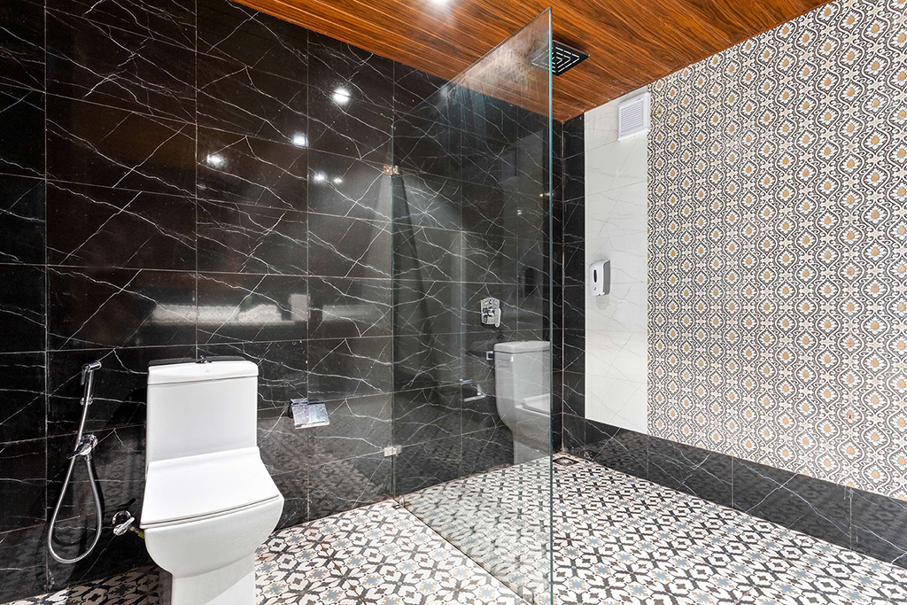 Bathroom with black marble walls, patterned floor, and wood ceiling trim