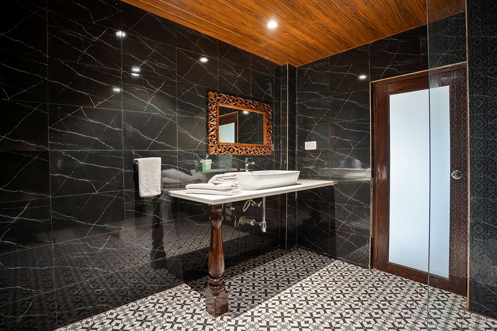 Modern bathroom with black marble, patterned floor, and vessel sink
