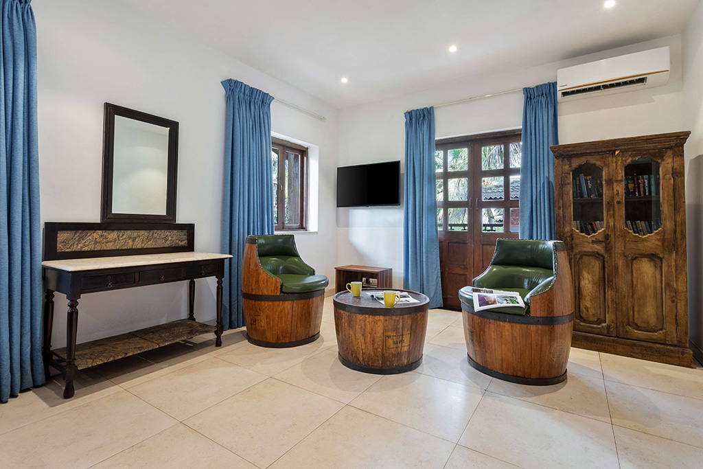Room with barrel-style armchairs, a wooden coffee table, and blue curtains.
