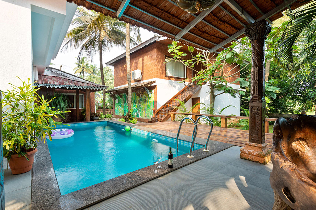 Bright private pool area next to a wooden deck and lush tropical foliage