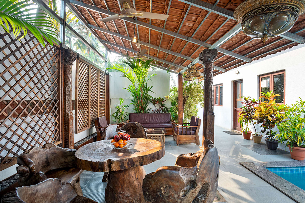 Covered outdoor dining and lounge area by a pool with rustic wooden furniture