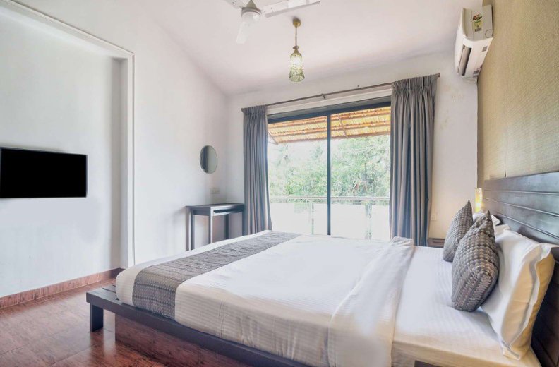 Villa bedroom with double bed, wooden floor and balcony doors