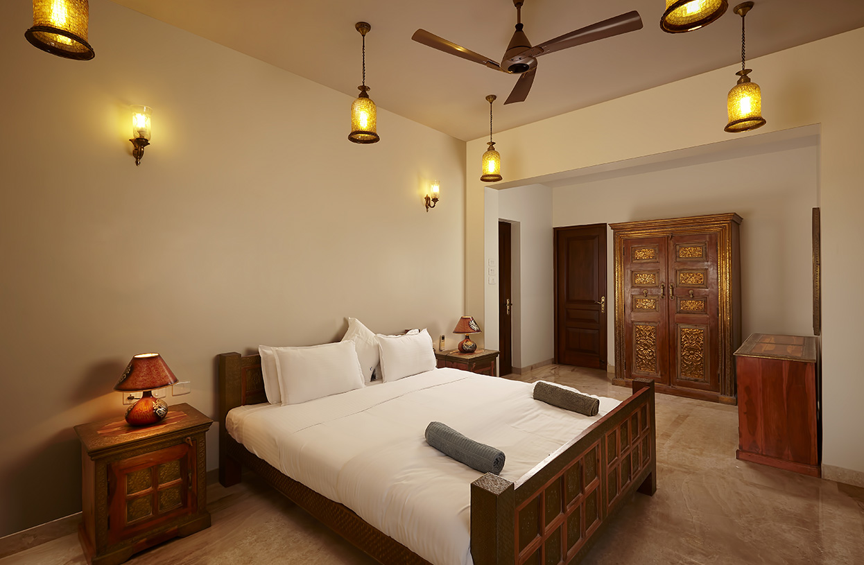 Cozy bedroom with carved wooden furniture, warm lighting, and spacious layout at Dolphin Heights