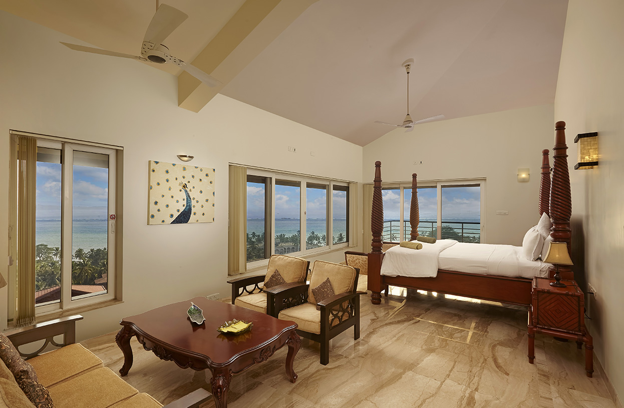 Luxury sea-view bedroom with large windows, elegant wooden furniture, and a cozy seating area at Dolphin Heights