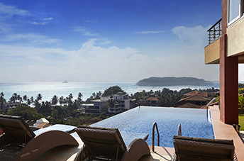 Infinity pool at Dolphin Heights overlooking the Arabian Sea with lounge chairs and a panoramic coastal view in Goa