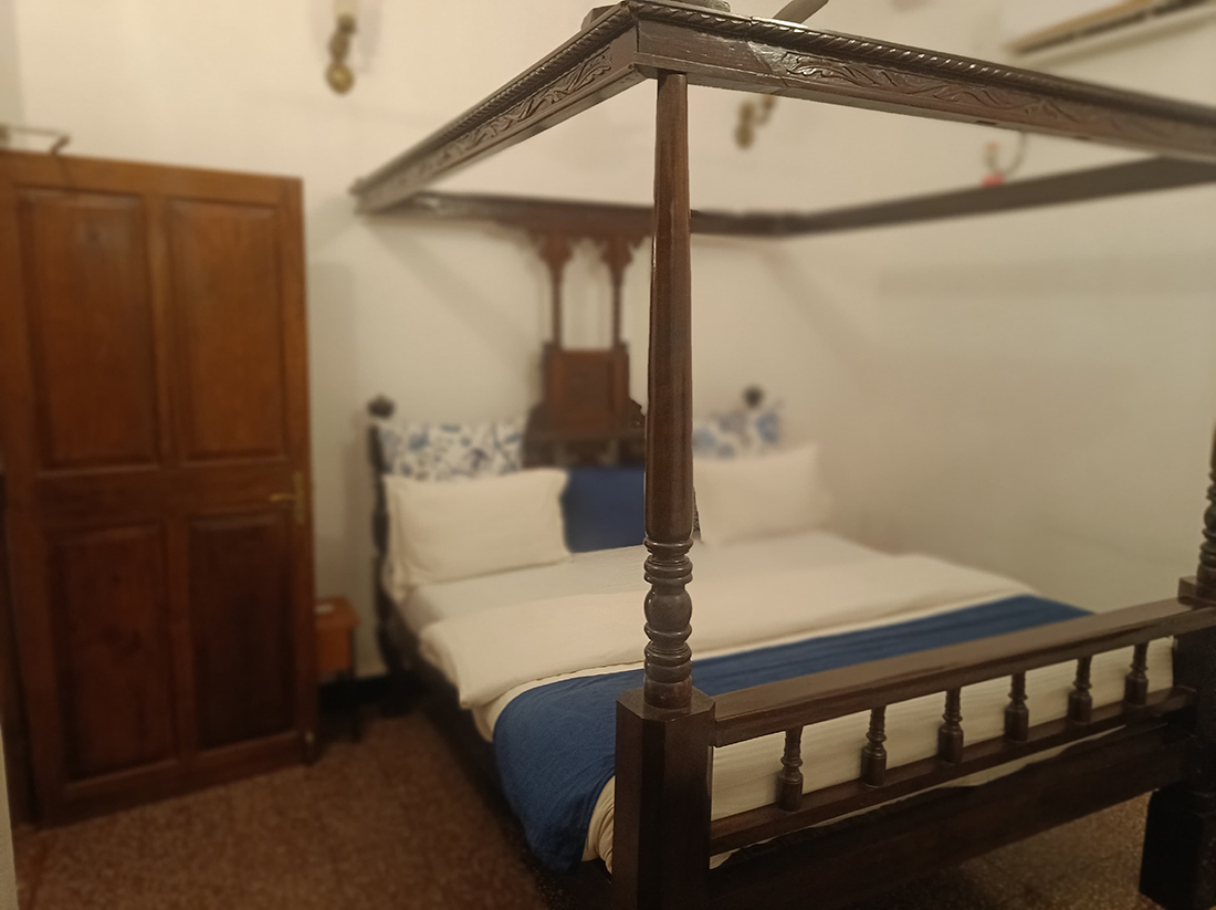Bedroom with a four-poster bed and wooden wardrobe.