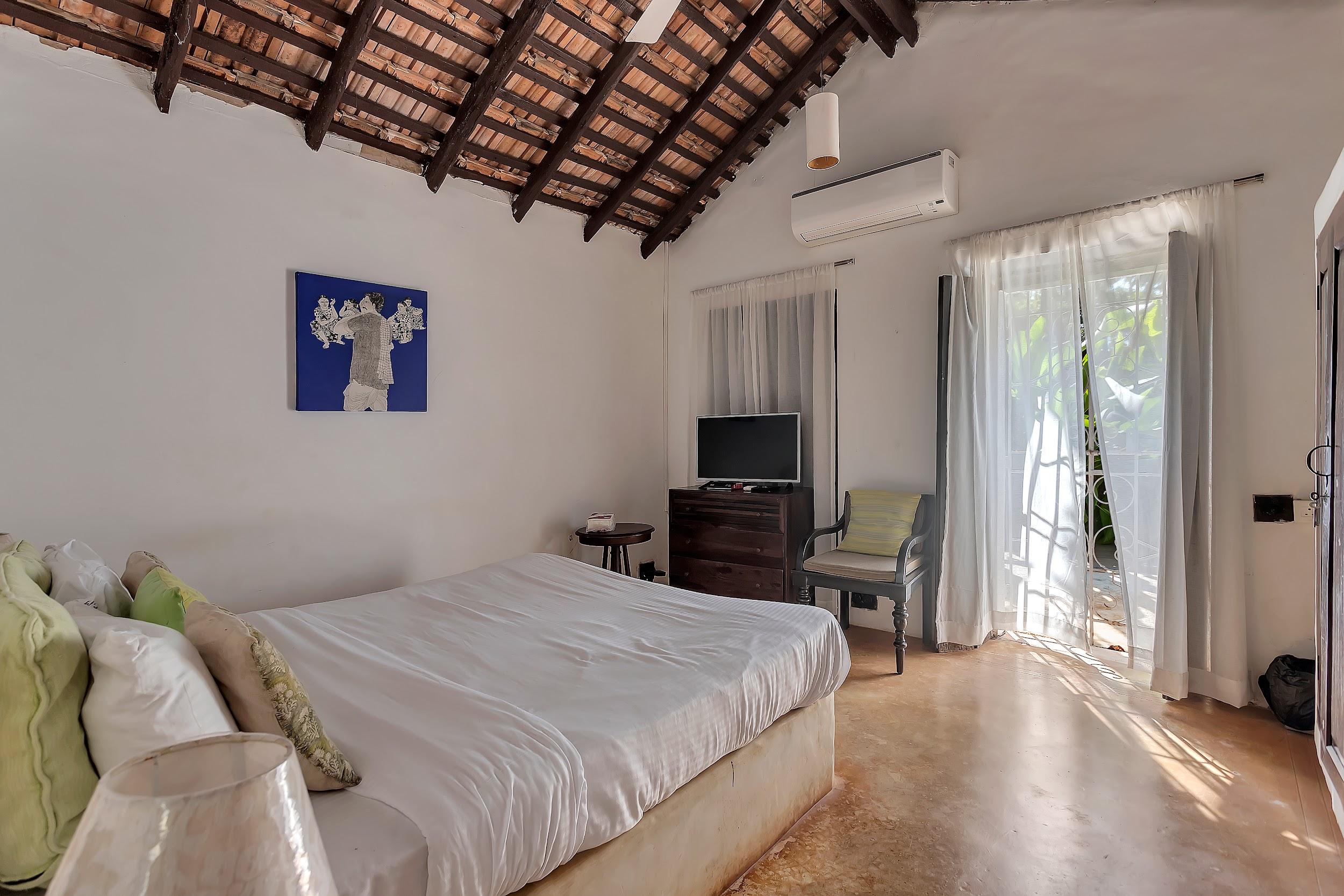 Bedroom with white sheer curtains opening to the outside, a TV, and a sloped wooden roof