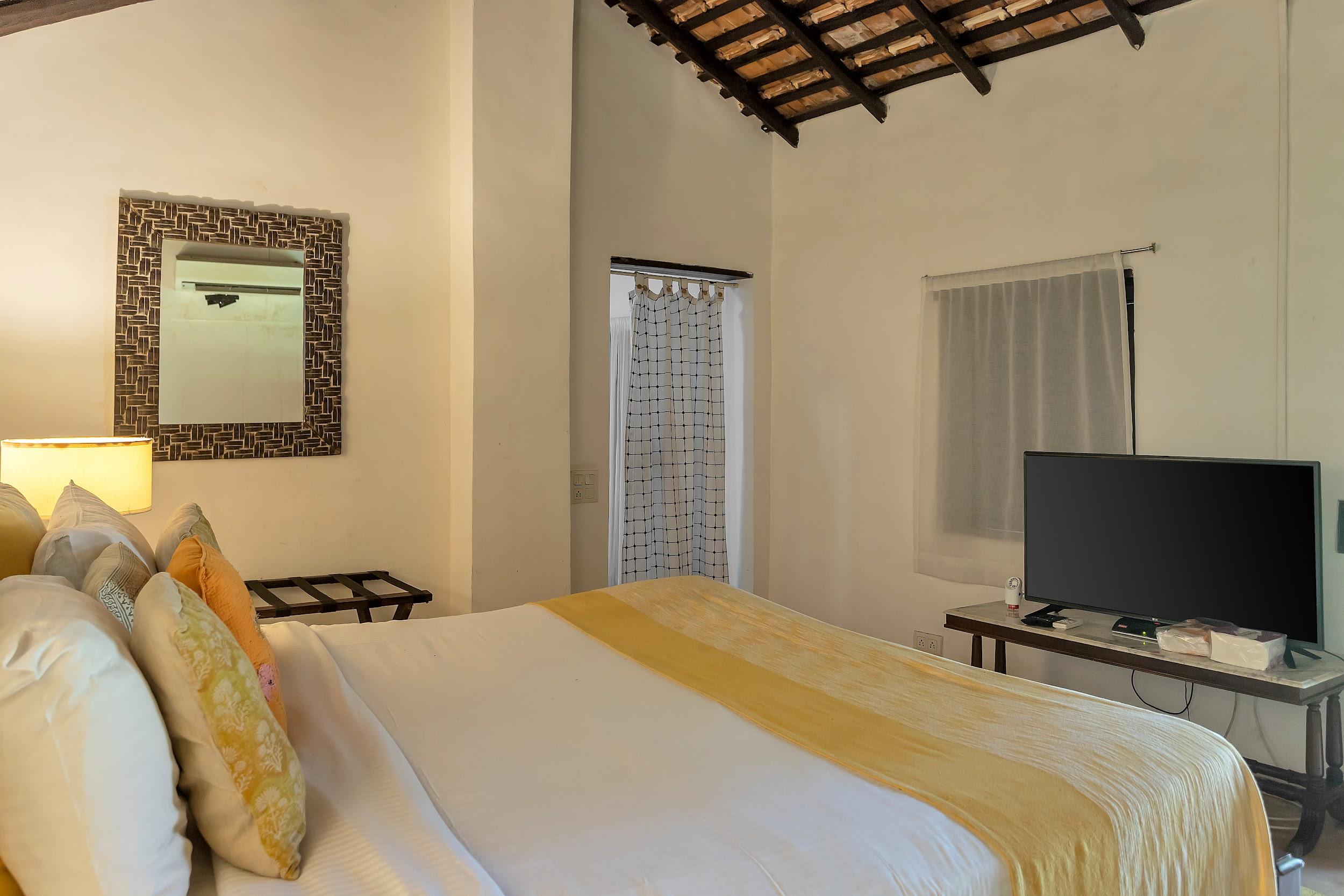 Bedroom with a yellow accent throw, flat-screen TV, and exposed terracotta roof rafters.