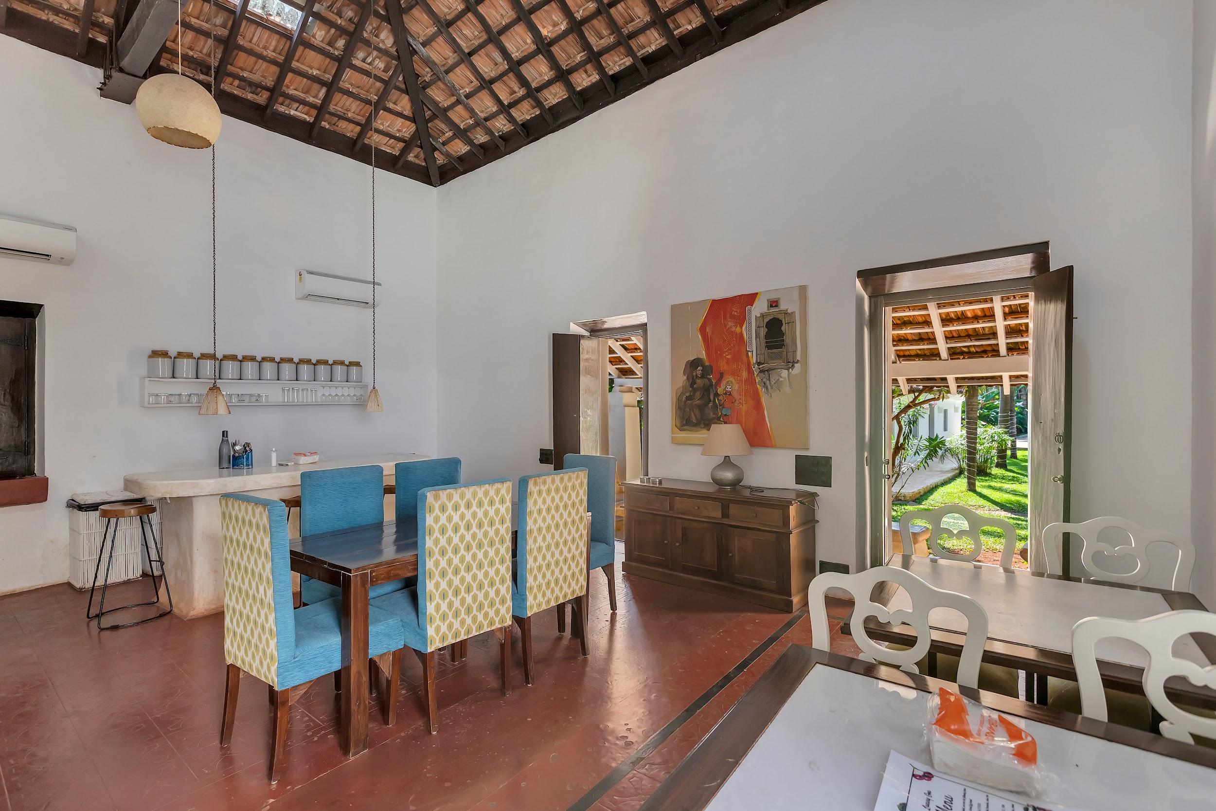 Interior dining space with bright blue chairs, a wooden table, and a view of the stairs and garden access