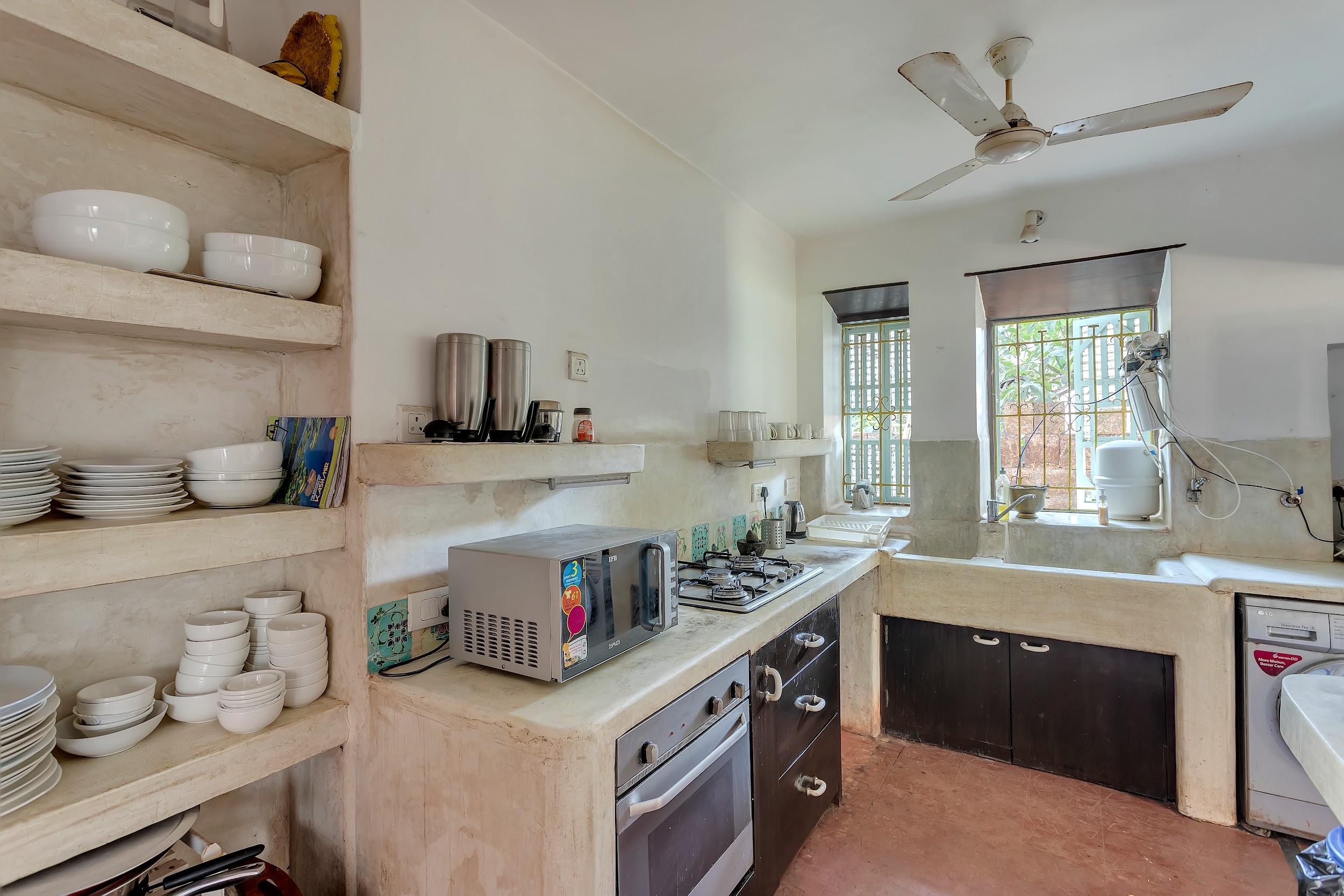 Bright kitchen interior with open shelving, a built-in oven/stove, and a ceiling fan