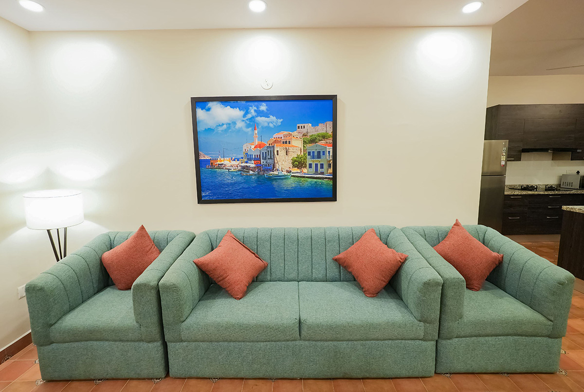 : Living room with green sofa, red accent pillows, and wall art