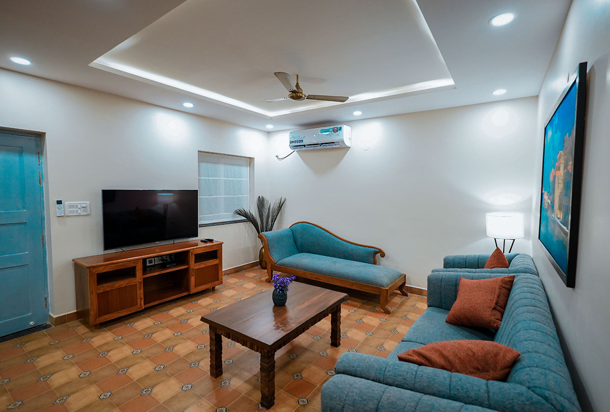 Cozy living room featuring TV, blue sofas, and wooden furniture